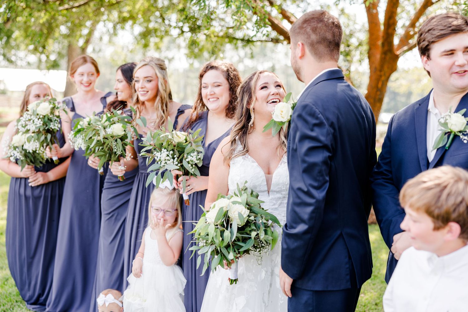 Wedding party laughs together during outdoor photo session.