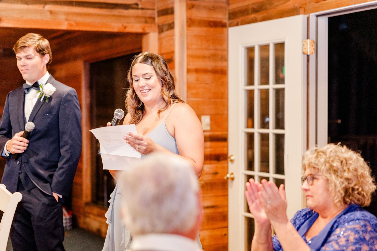 Wedding guests gather in a rustic wooden venue during a ceremony.
