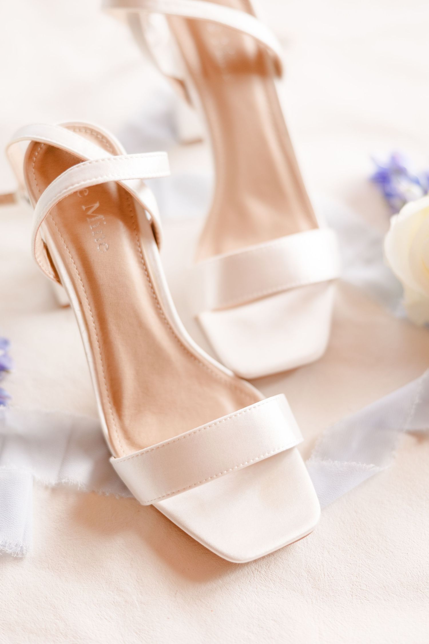 Elegant cream-colored bridal heels arranged in a soft, dreamy composition.