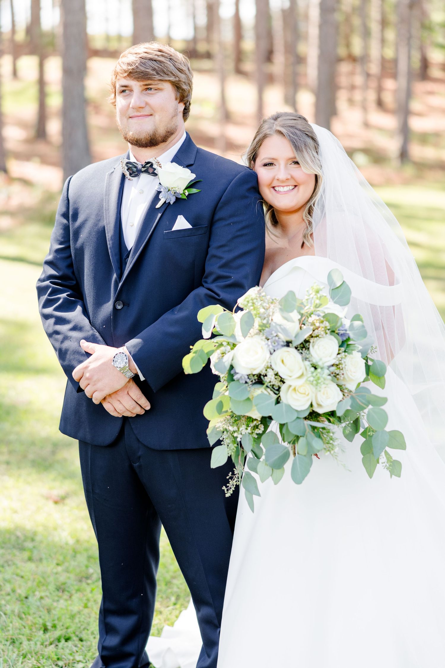 Classic formal wedding portrait of couple in navy suit and white dress with eucalyptus bouquet.