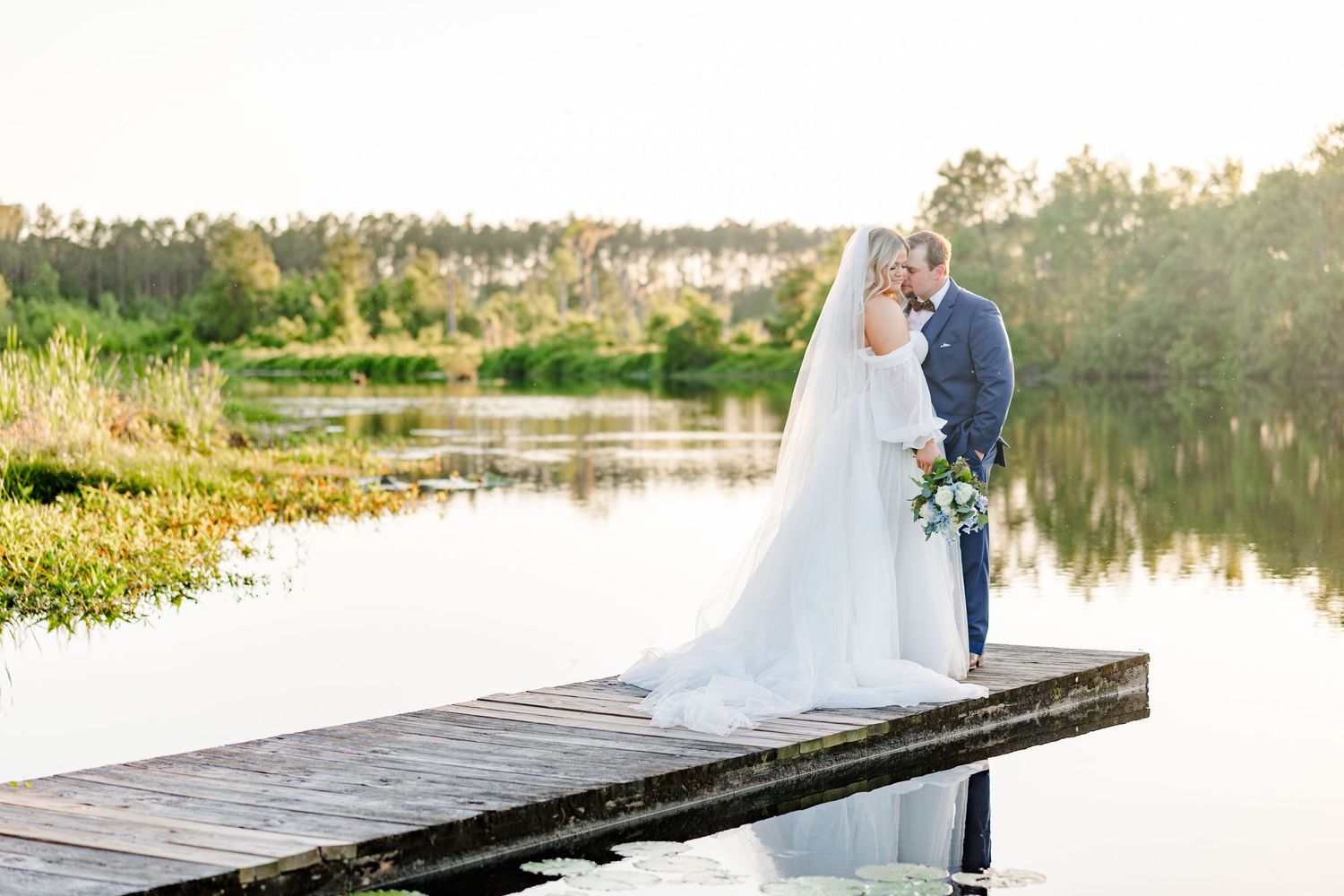 Romantic dock photos at sunset with bride and groom silhouetted against water.