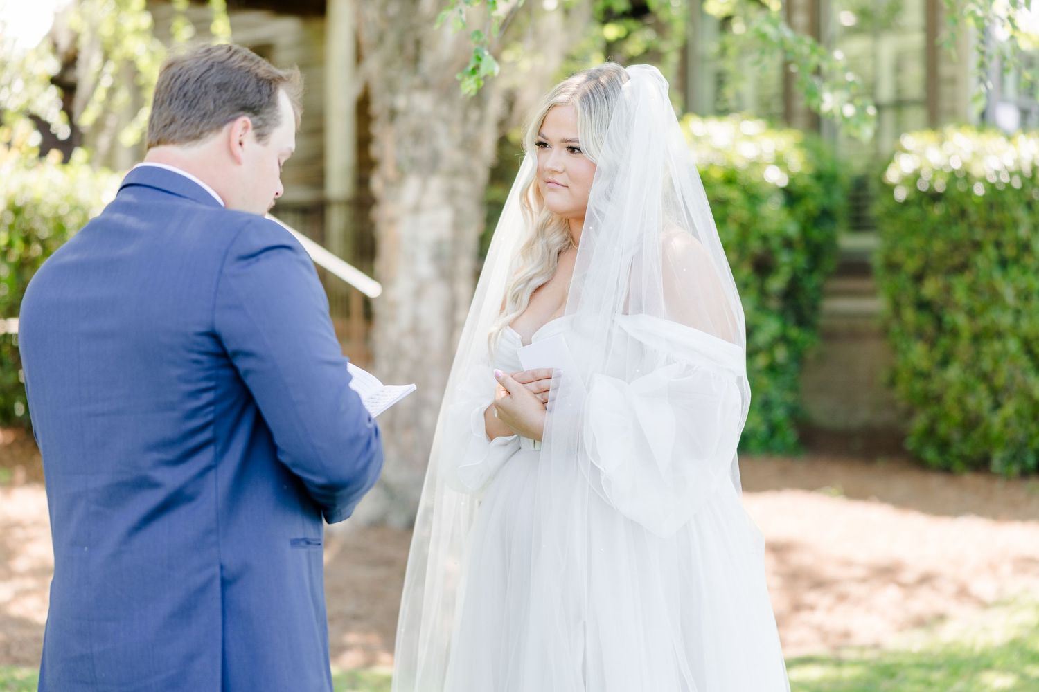 Tender moment between newlyweds during outdoor garden ceremony.