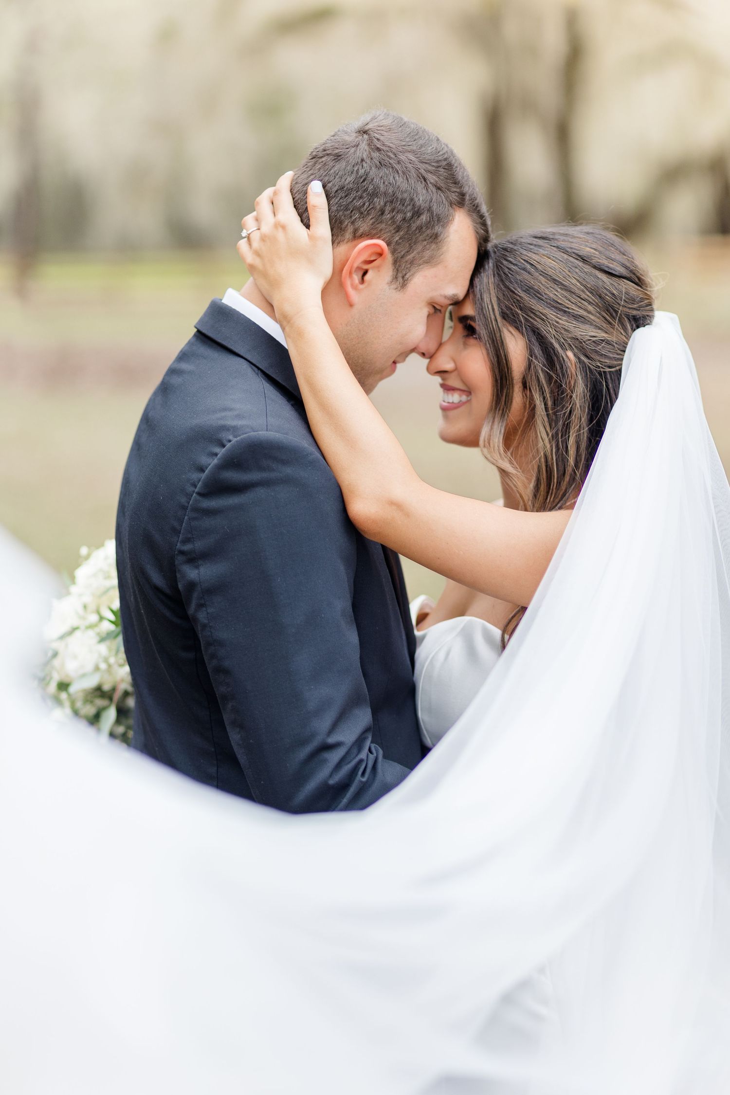 An intimate wedding moment captured as a couple shares a tender embrace outdoors.