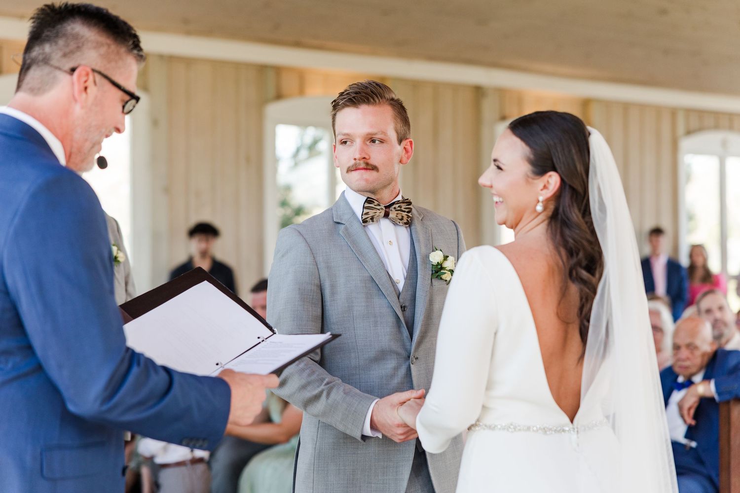 Wedding ceremony taking place inside a bright wooden chapel with guests in attendance.