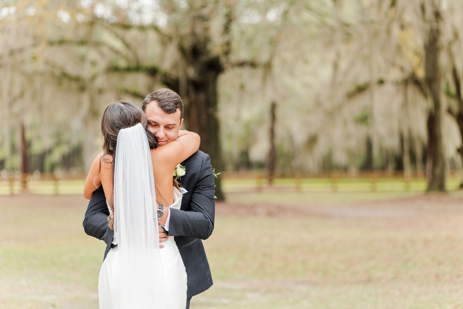 A romantic first look wedding moment captured in a natural outdoor setting with trees.