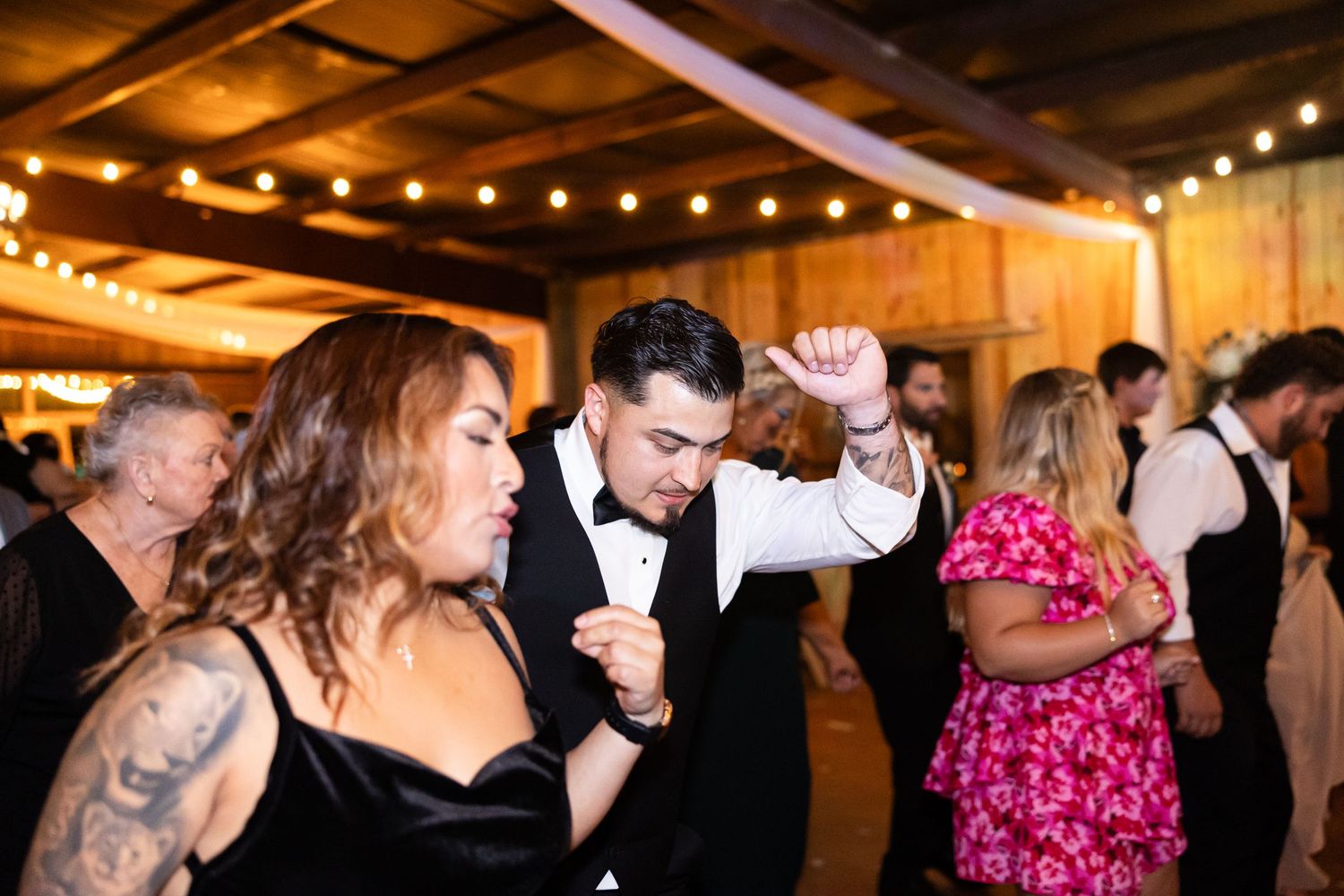 Wedding guests dancing and celebrating on the dance floor at reception.