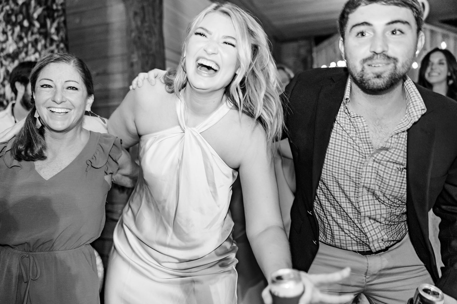 Black and white photo of wedding guests dancing and celebrating at reception.