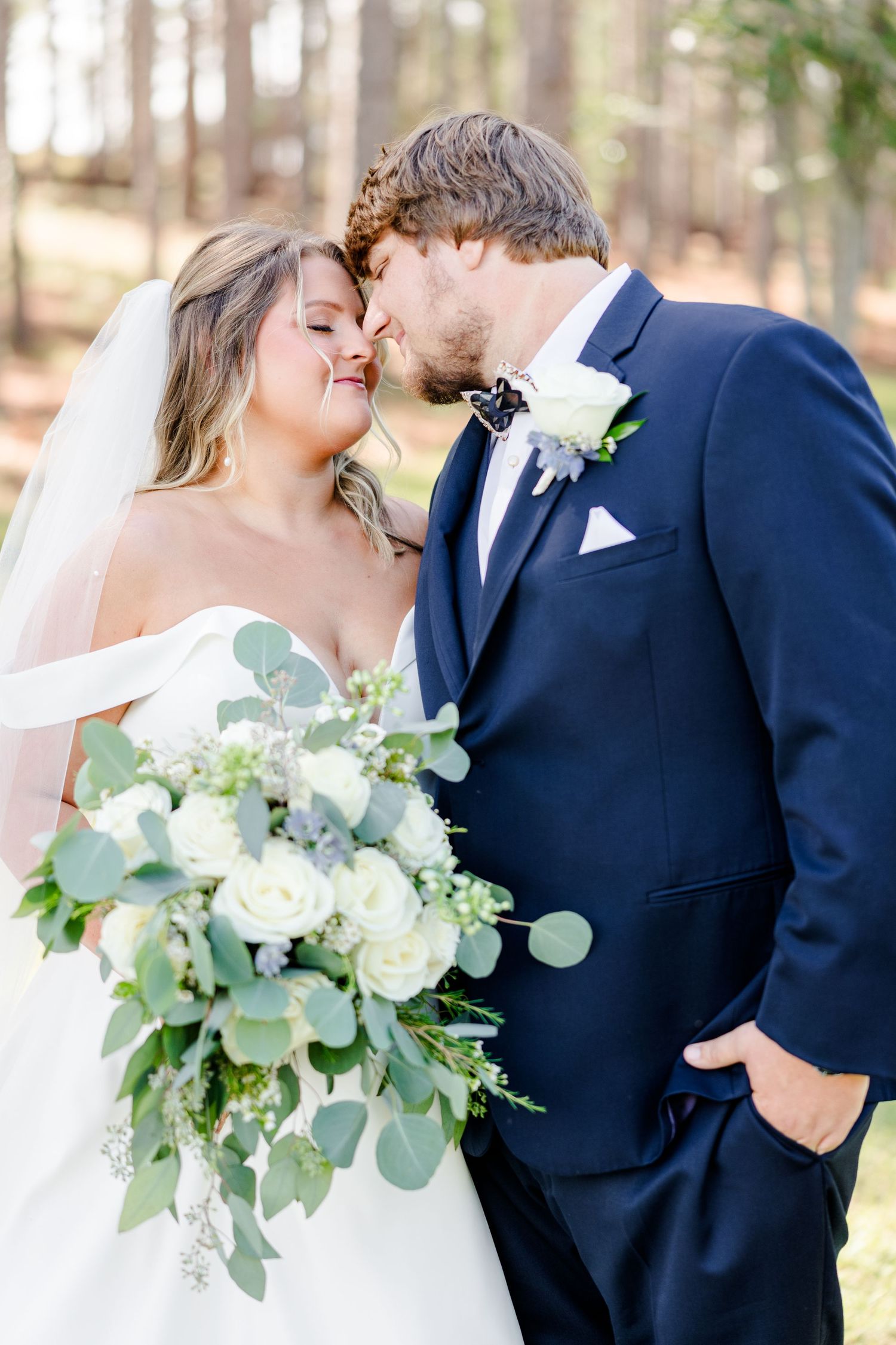 Bride holding white and green bouquet shares intimate moment with groom.