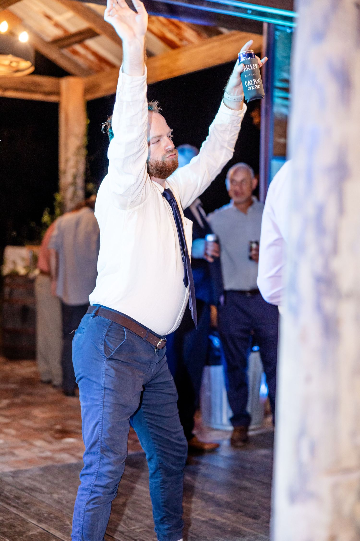 Energetic dancing at a wedding reception with guests raising their arms in celebration.