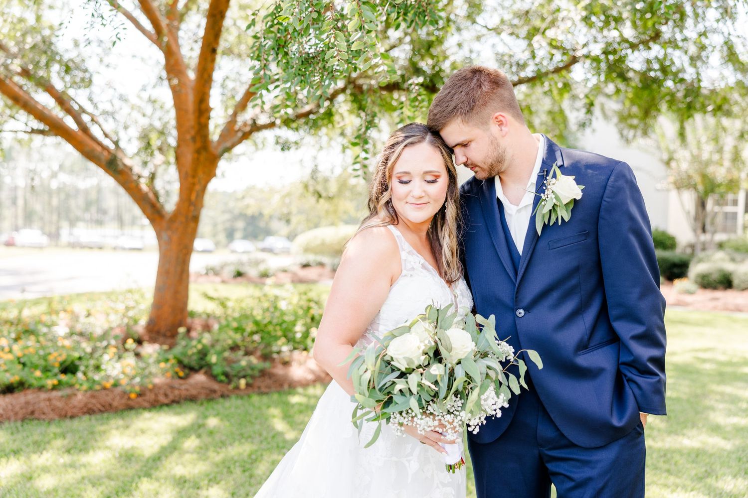 Sun-filled garden wedding portraits featuring elegant couple beneath flowering trees.
