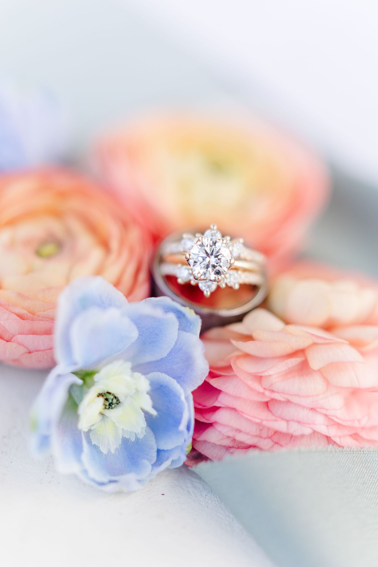 A stunning diamond engagement ring nestled among pink and blue flowers.