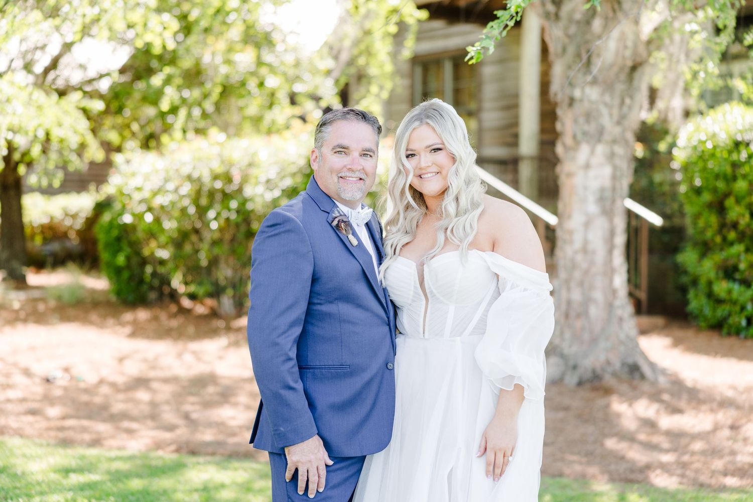Elegant outdoor wedding portraits with couple in white dress and navy suit among trees.
