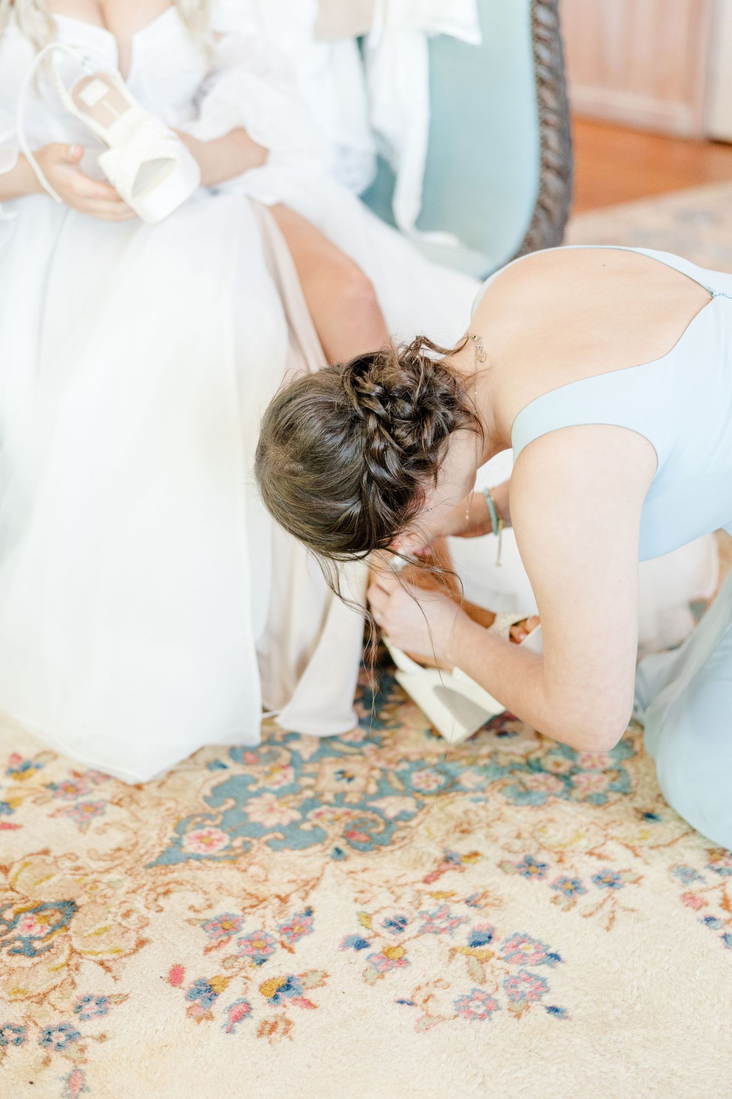 Wedding preparation moments captured on ornate floral carpet in natural light.