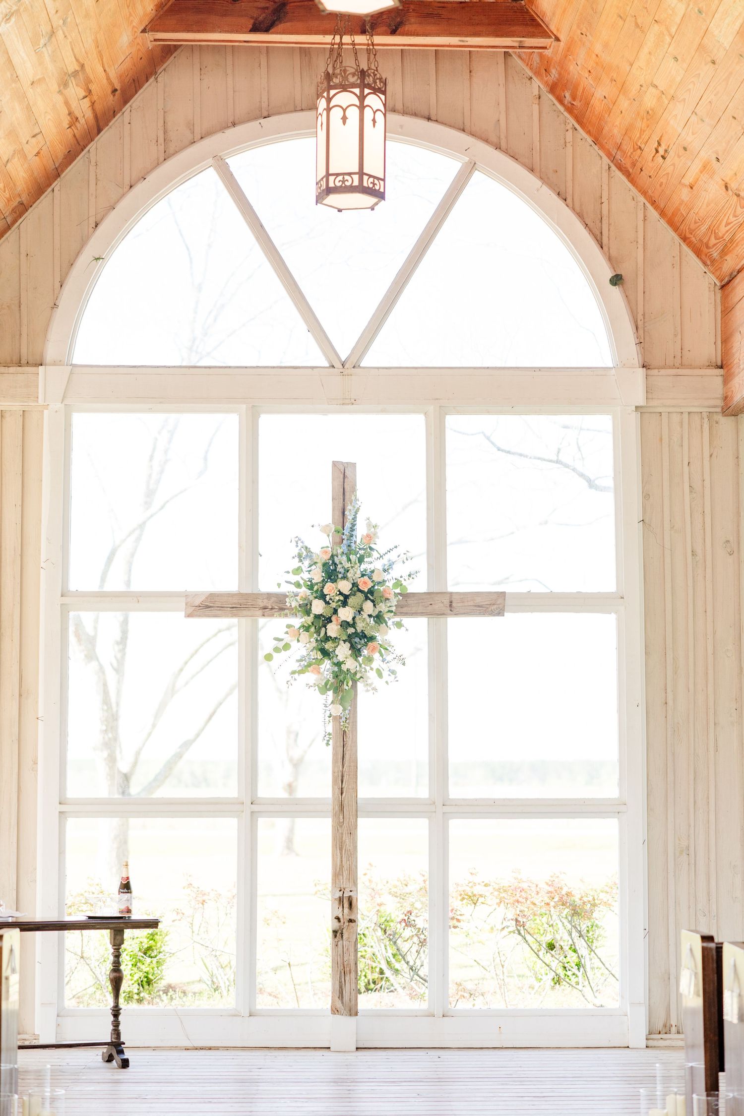 An elegant white chapel interior with vaulted ceilings and arched windows filled with natural light.