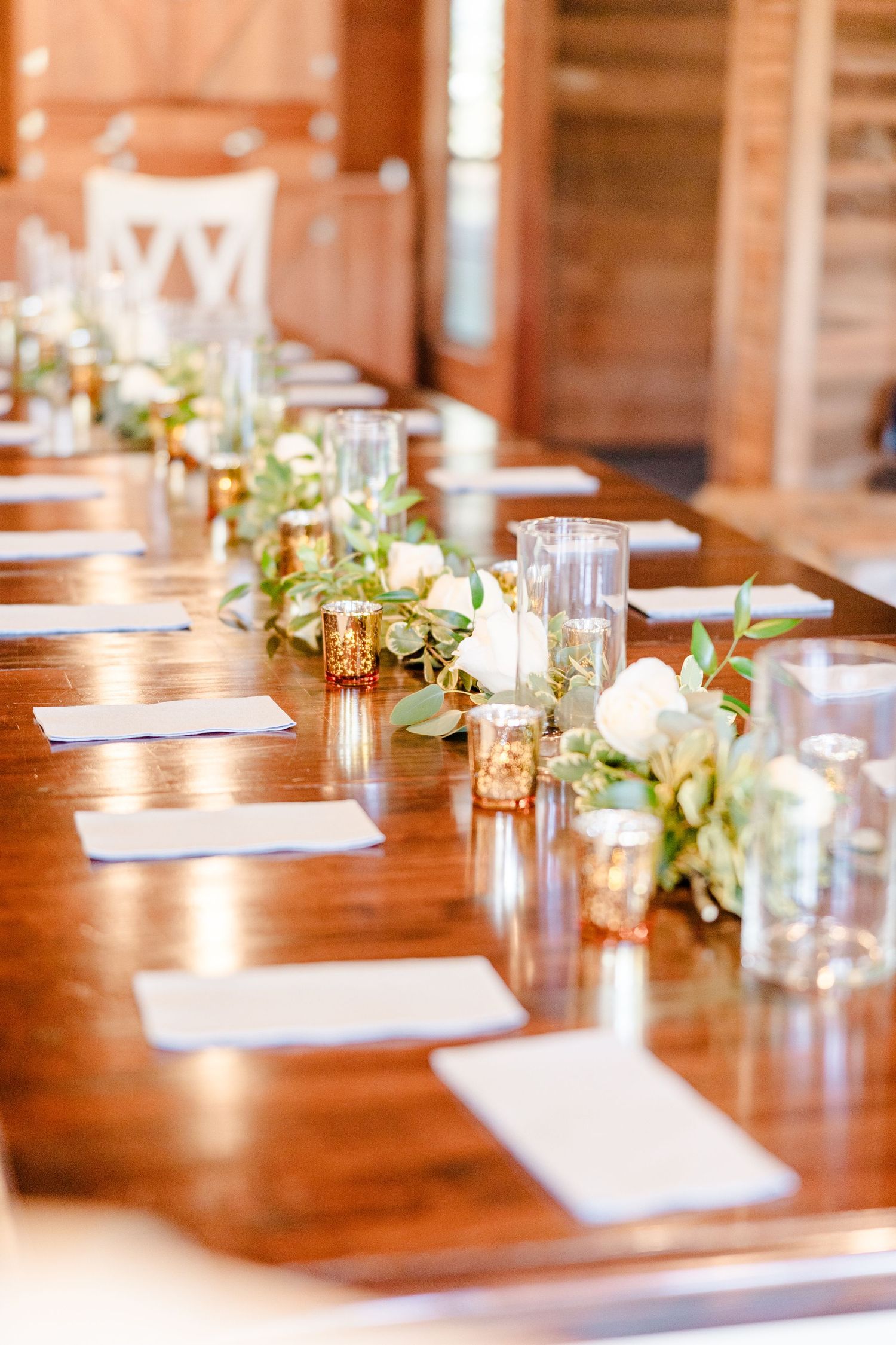 Rustic wooden dining table set with elegant place settings and floral centerpieces.