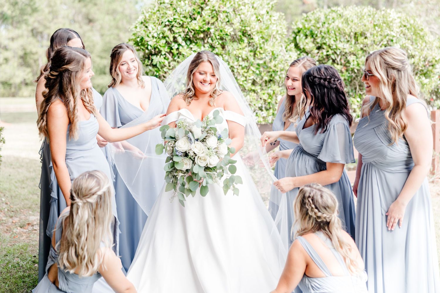 Wedding party in light blue bridesmaid dresses gathered outdoors.