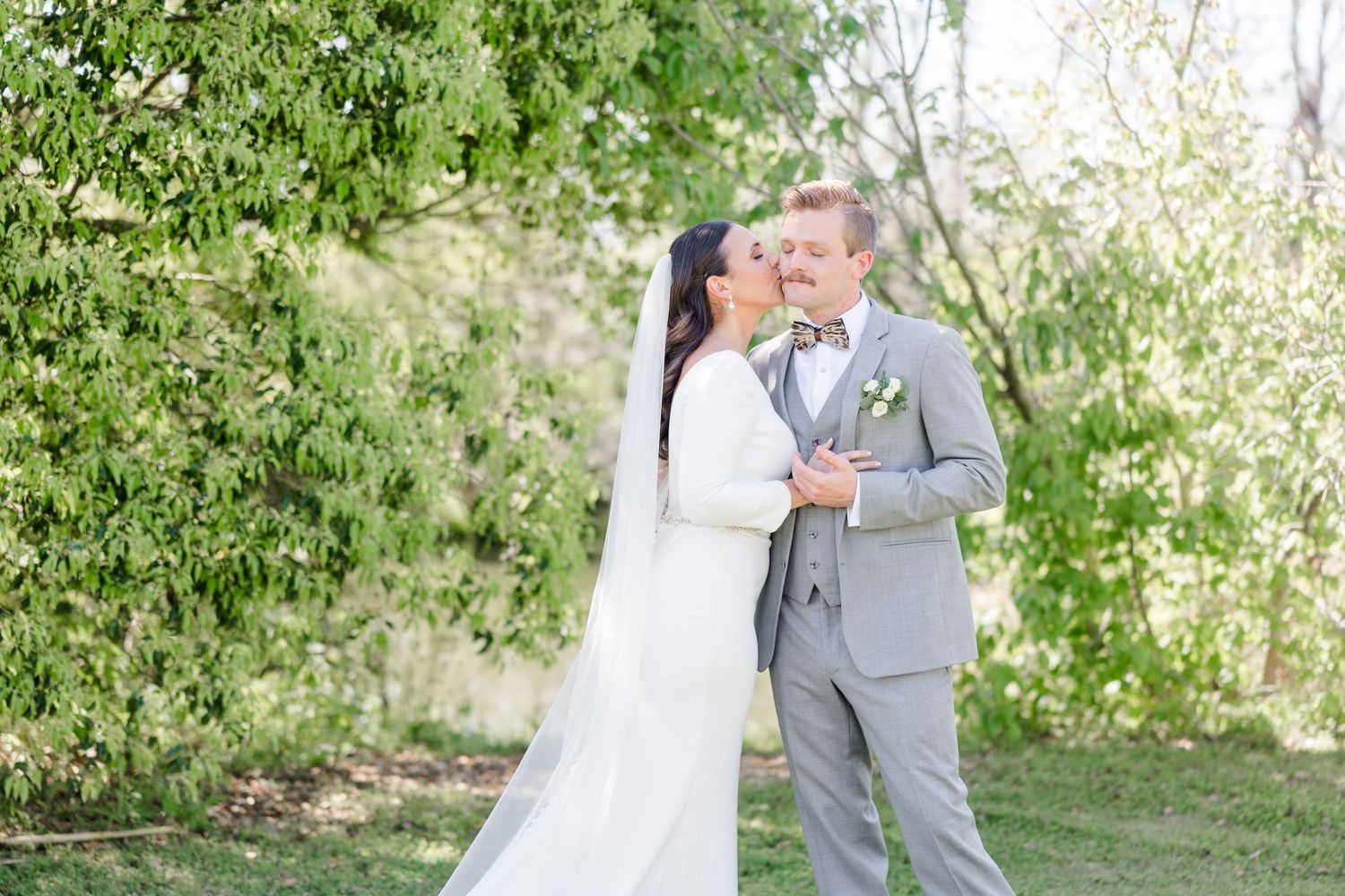 A couple exchanges vows during their outdoor wedding ceremony surrounded by spring foliage.