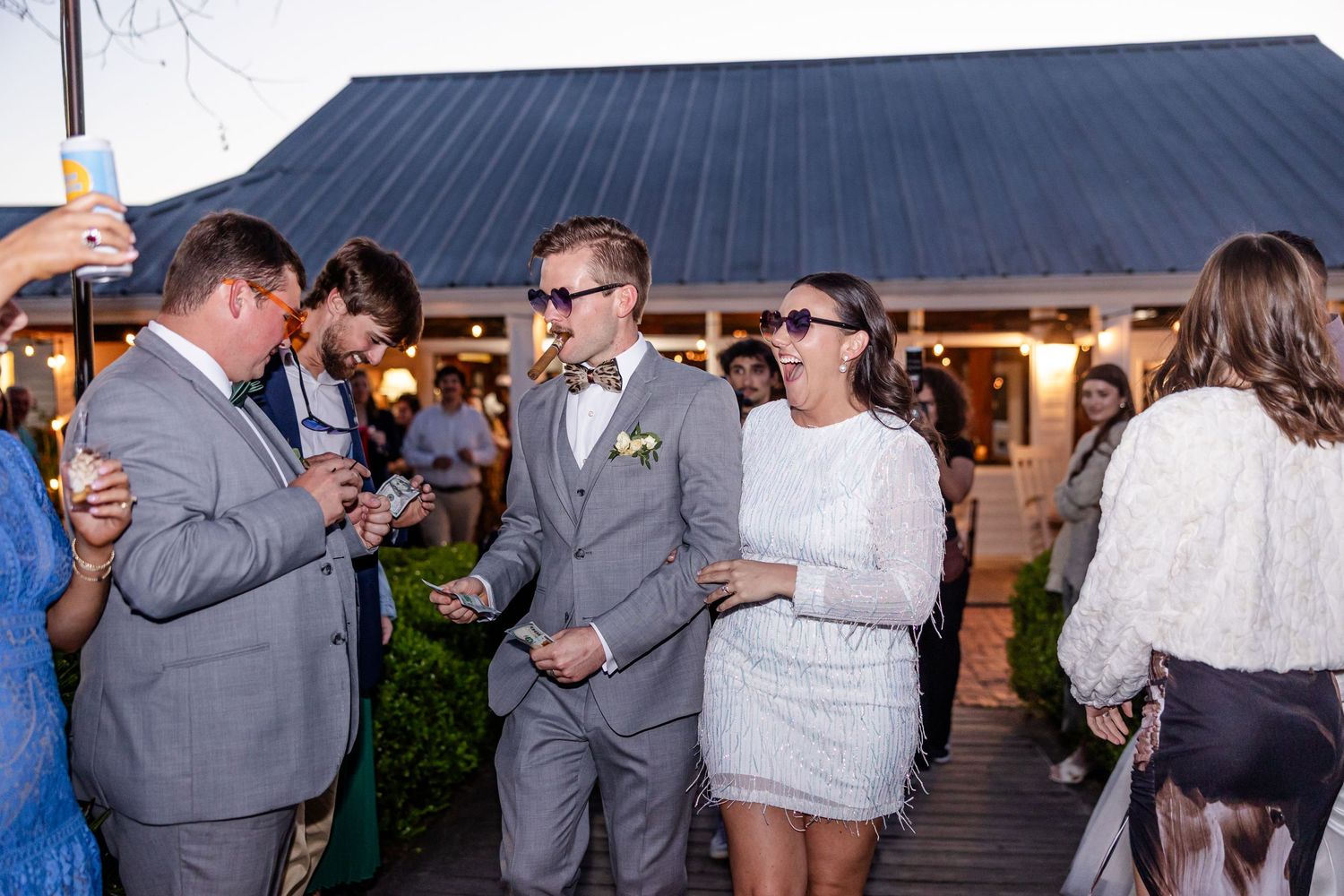 Group of guests mingling at an outdoor wedding reception near a rustic building.