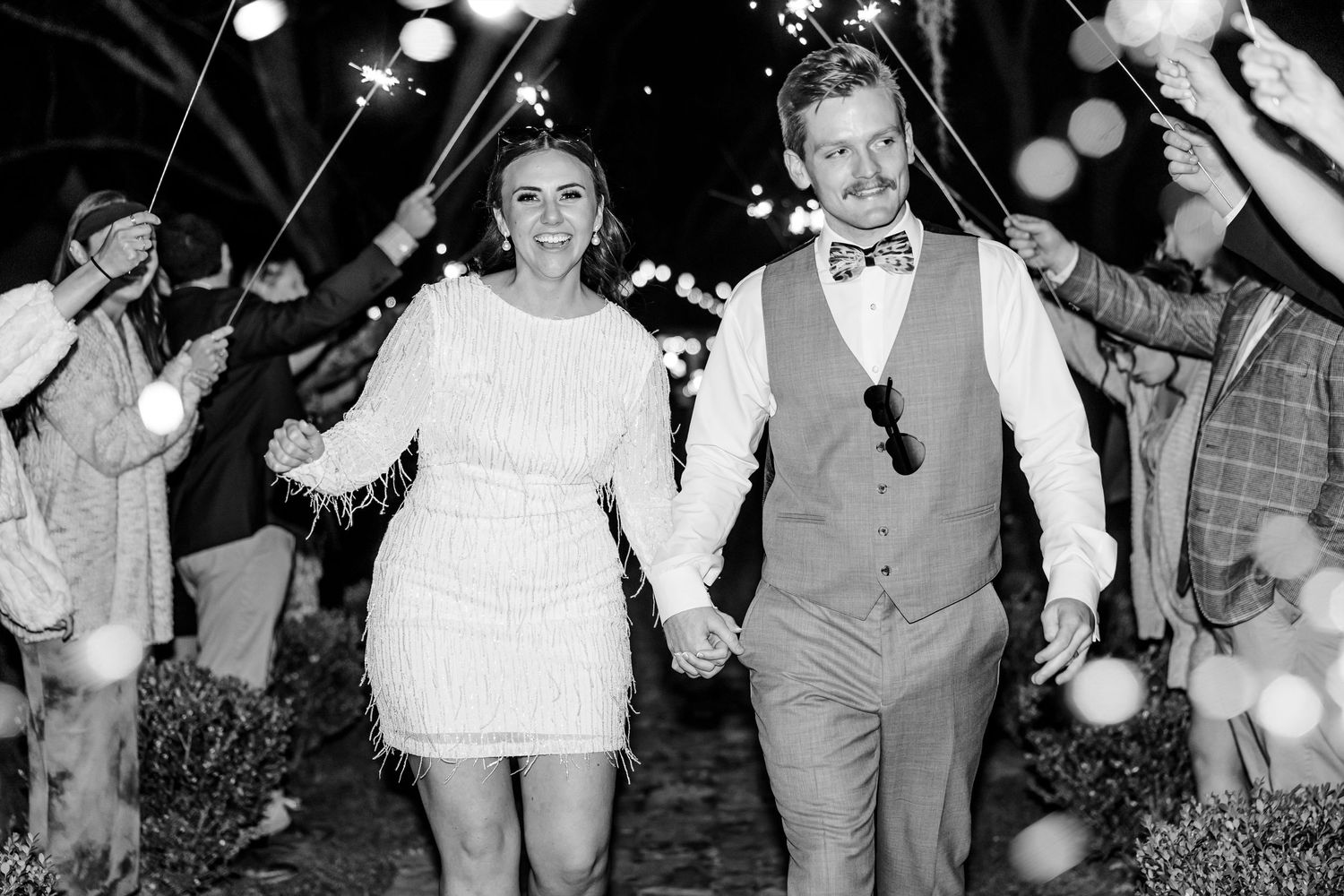 Black and white photo of newlyweds walking through sparkler exit at their reception.