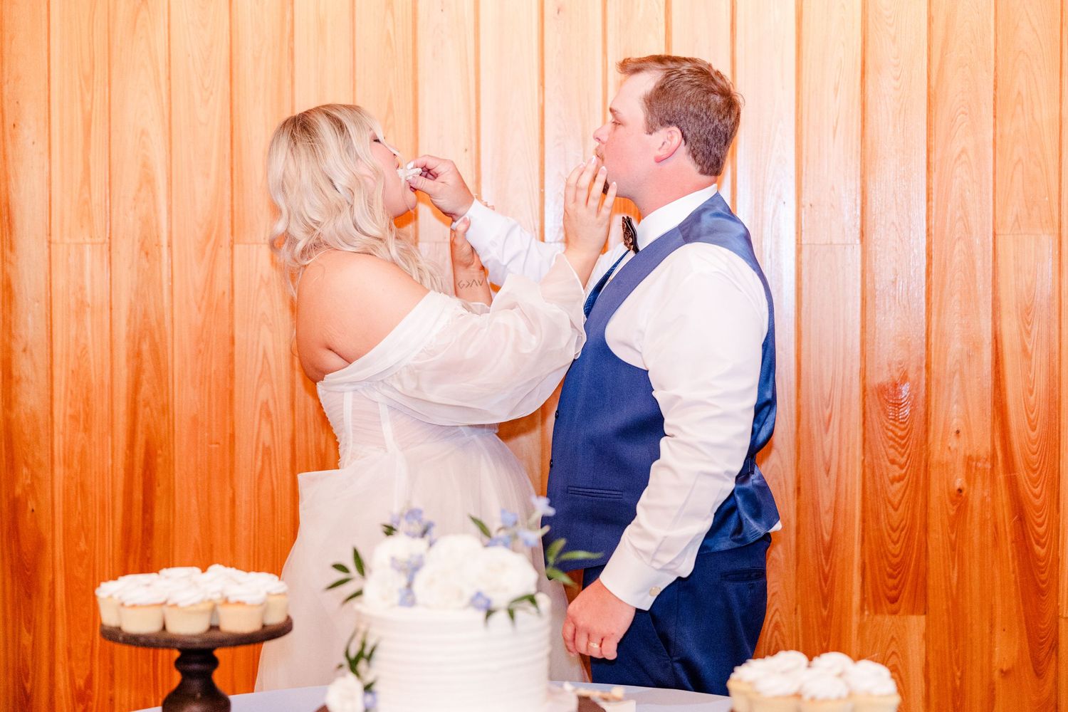 Wedding guests dancing and celebrating against warm orange wooden wall backdrop.