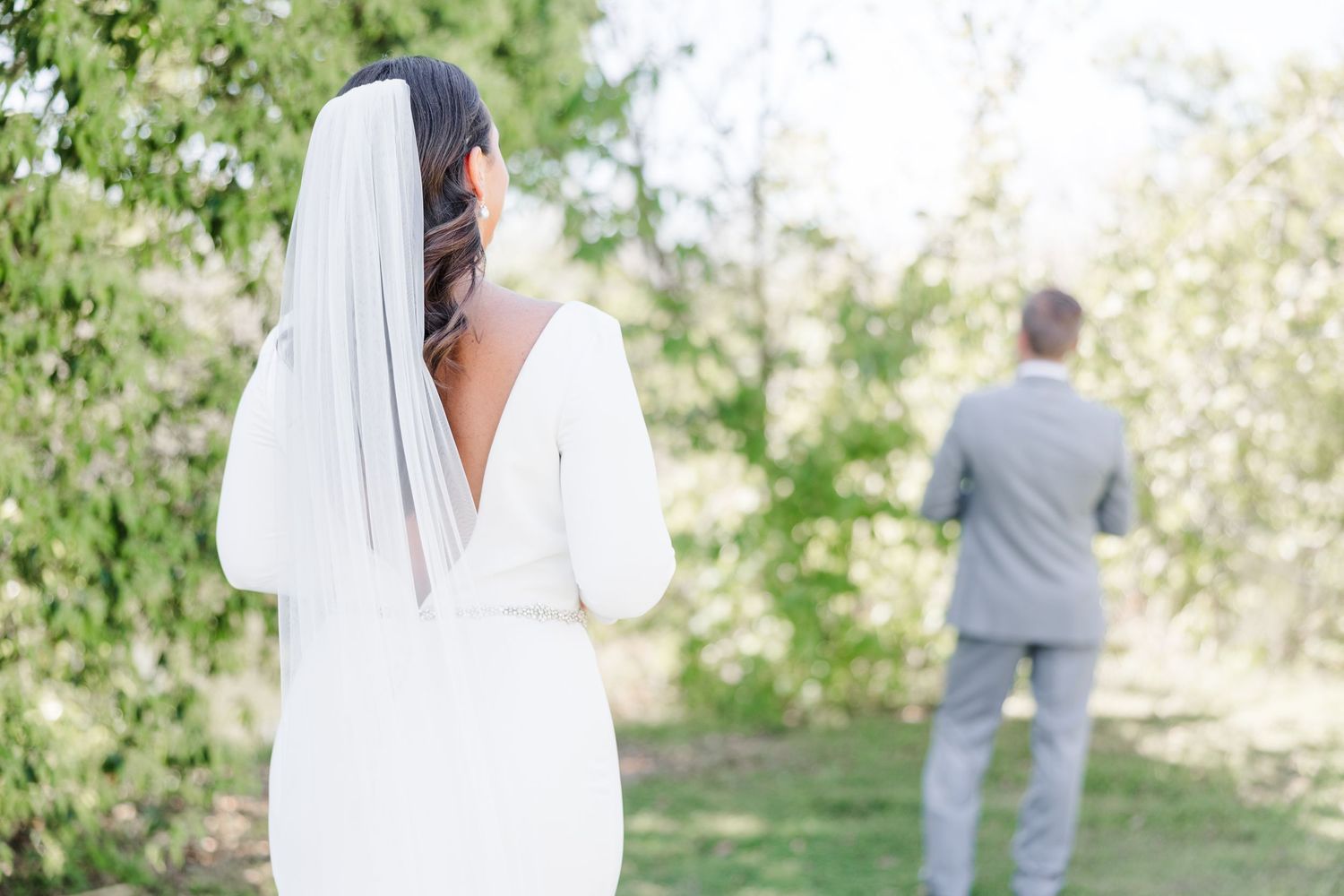 A couple shares an intimate first look moment in a garden setting with lush greenery.