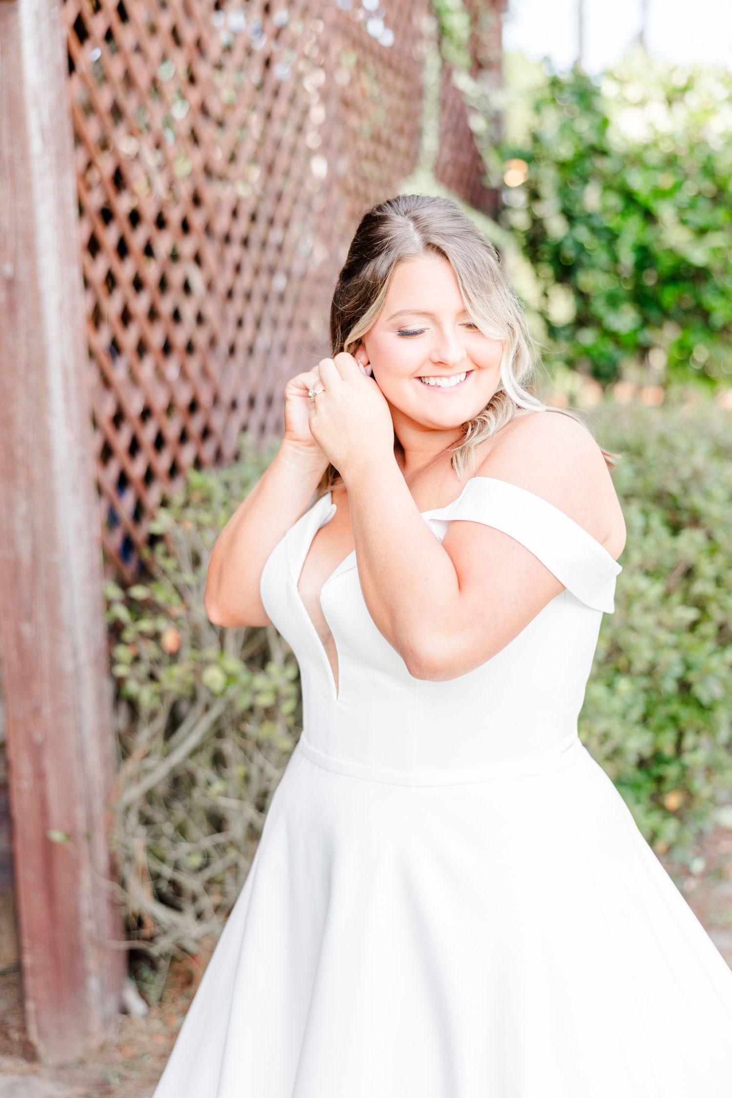 White dress twirling in an outdoor garden setting with lattice backdrop.