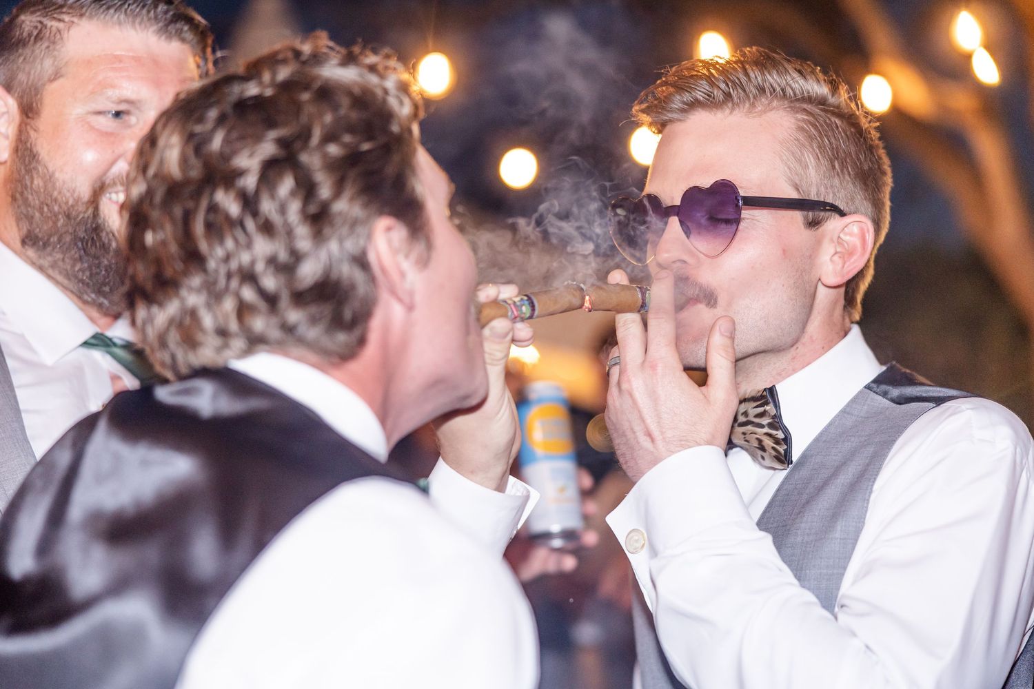 Guests sharing a smoke and conversation during an evening celebration with ambient lighting.