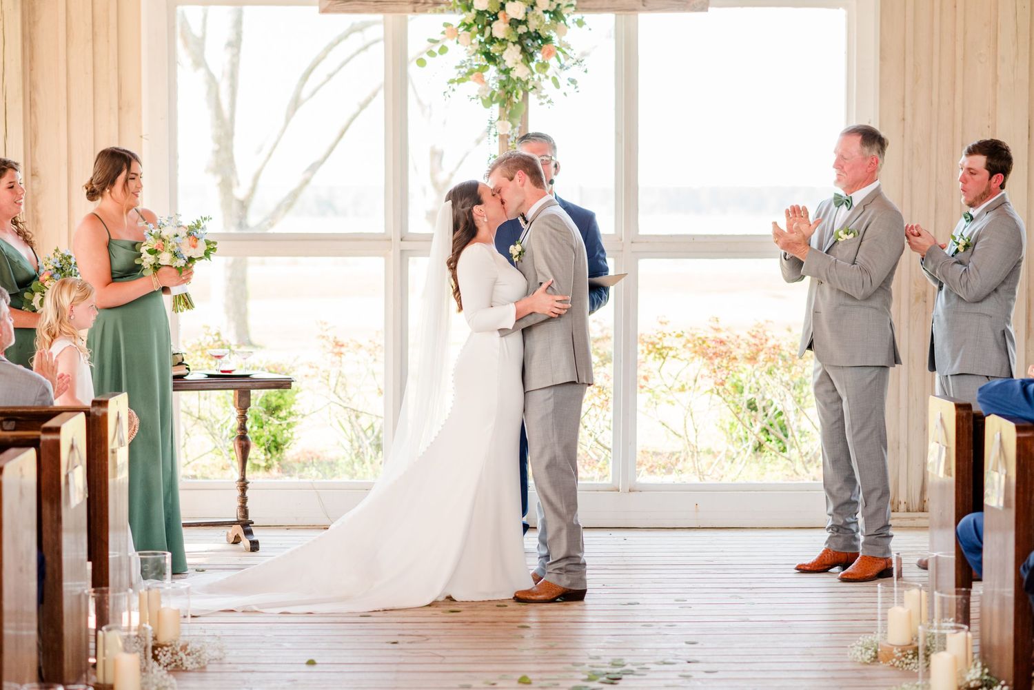 Elegant wedding ceremony in a light-filled chapel with wooden beams and arched windows.