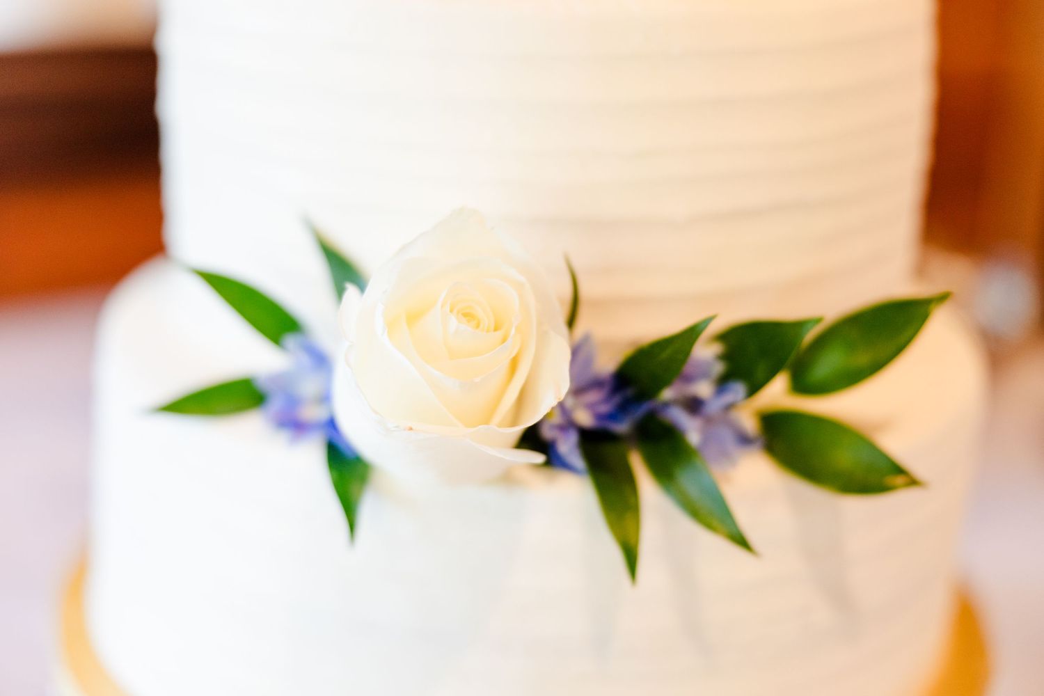An elegant white wedding cake decorated with delicate purple flowers and green leaves.