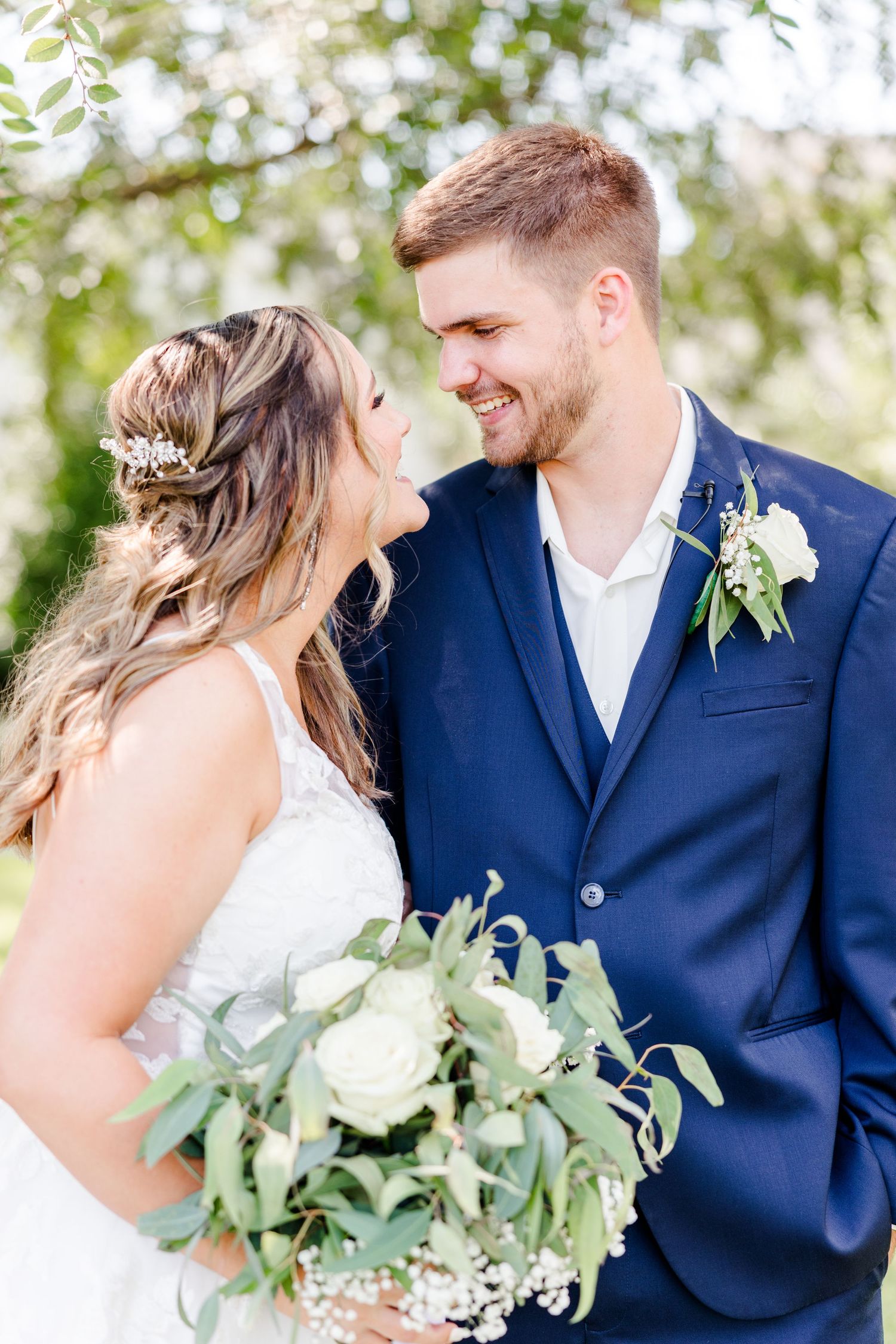 Candid wedding photography showing joyful couple with eucalyptus bouquet outdoors.