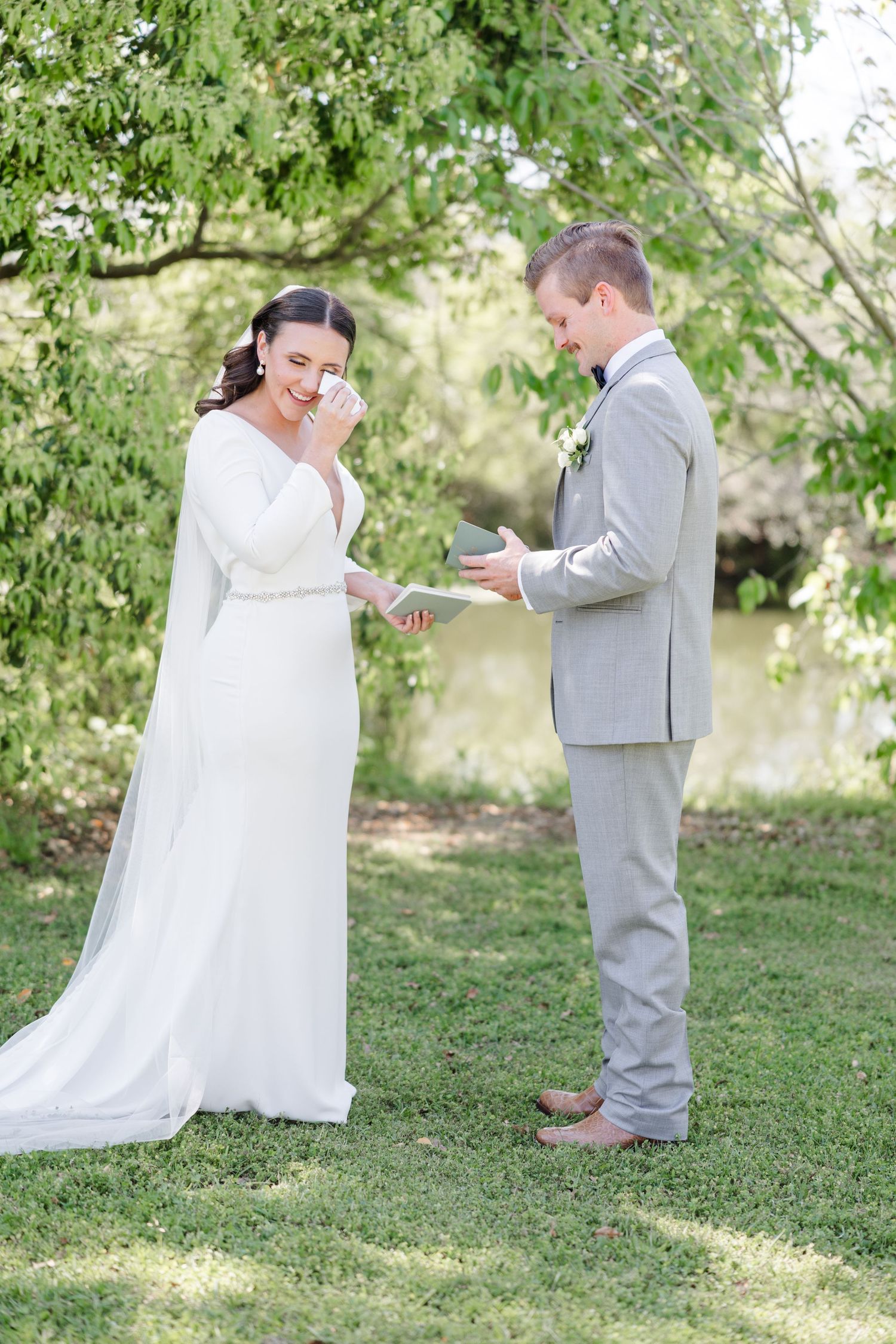 A couple shares a tender moment during their outdoor wedding ceremony on a grassy lawn.