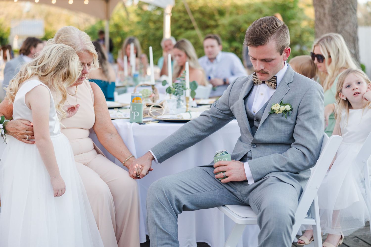 Wedding guests seated at outdoor reception tables in formal attire.