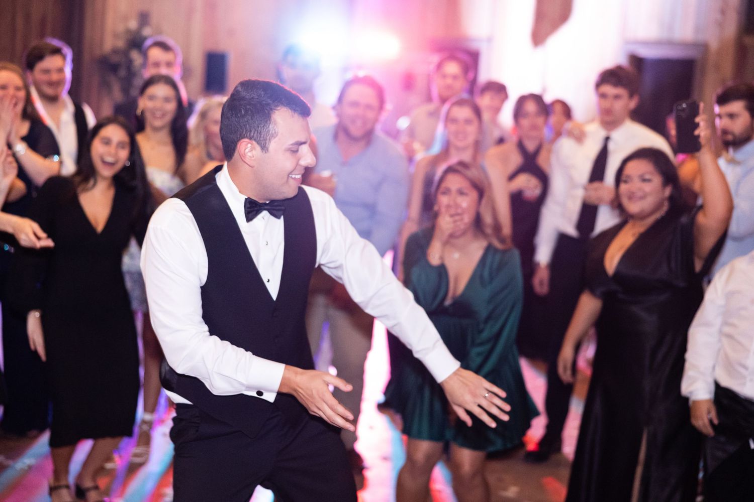 Guest performing dance moves for enthusiastic crowd at wedding reception.