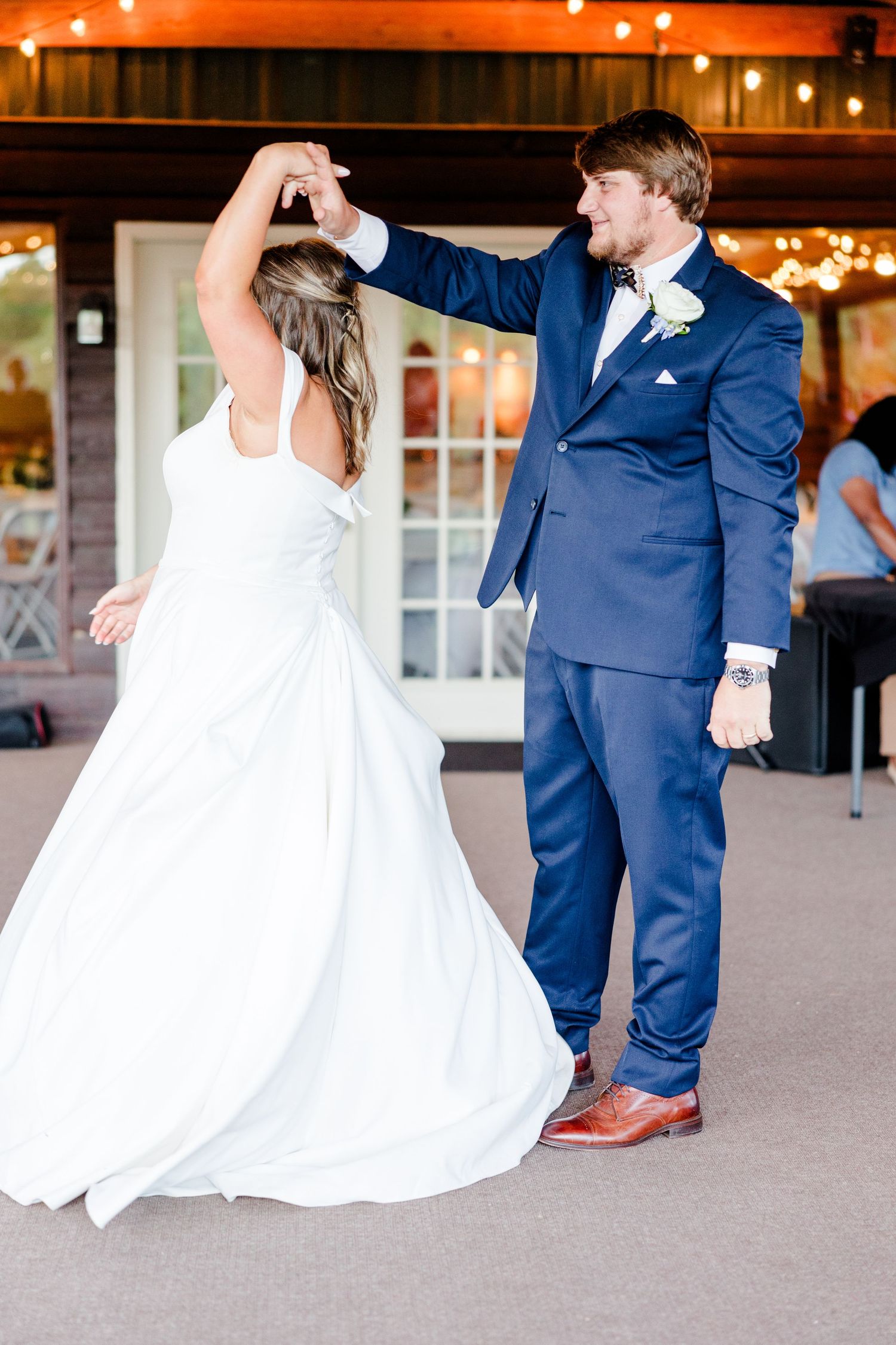 A couple performs their first dance at a wedding reception under warm lighting.