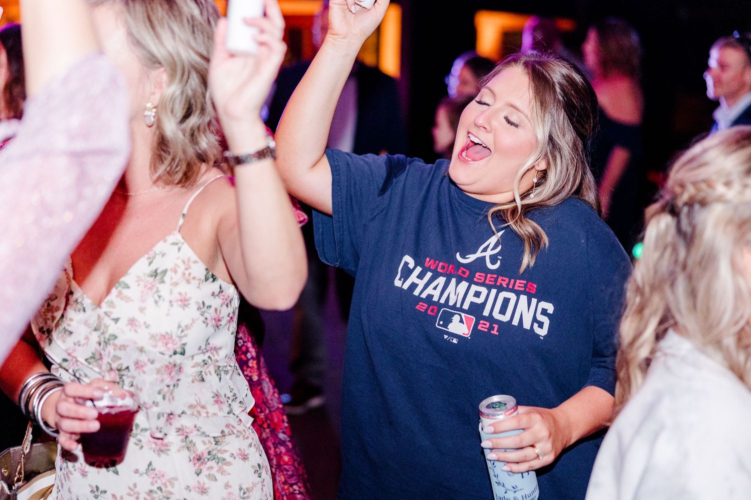 Guests dancing and celebrating at a lively wedding reception party with colorful lighting.