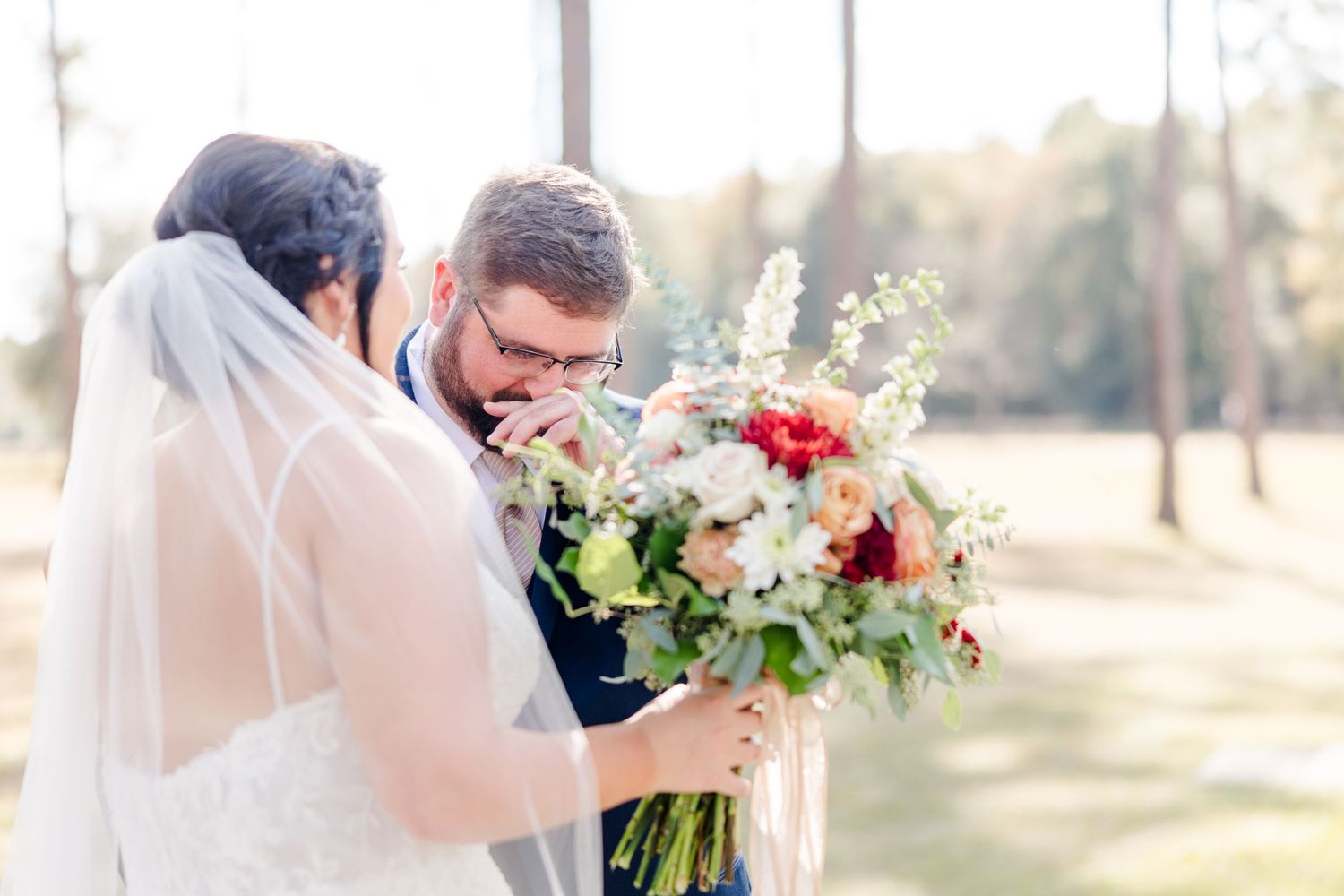 Bride and groom share intimate first look moment in outdoor garden setting.