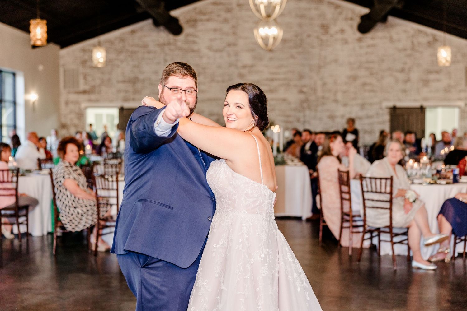 Couple sharing a dance moment in rustic stone venue with elegant lighting.
