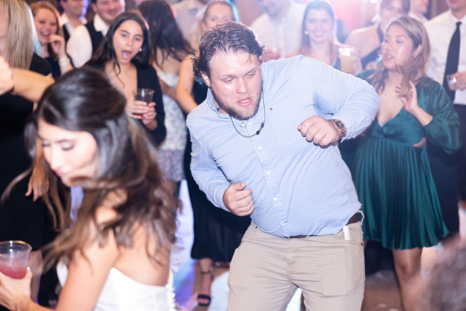 Wedding guest dancing enthusiastically on crowded reception dance floor.