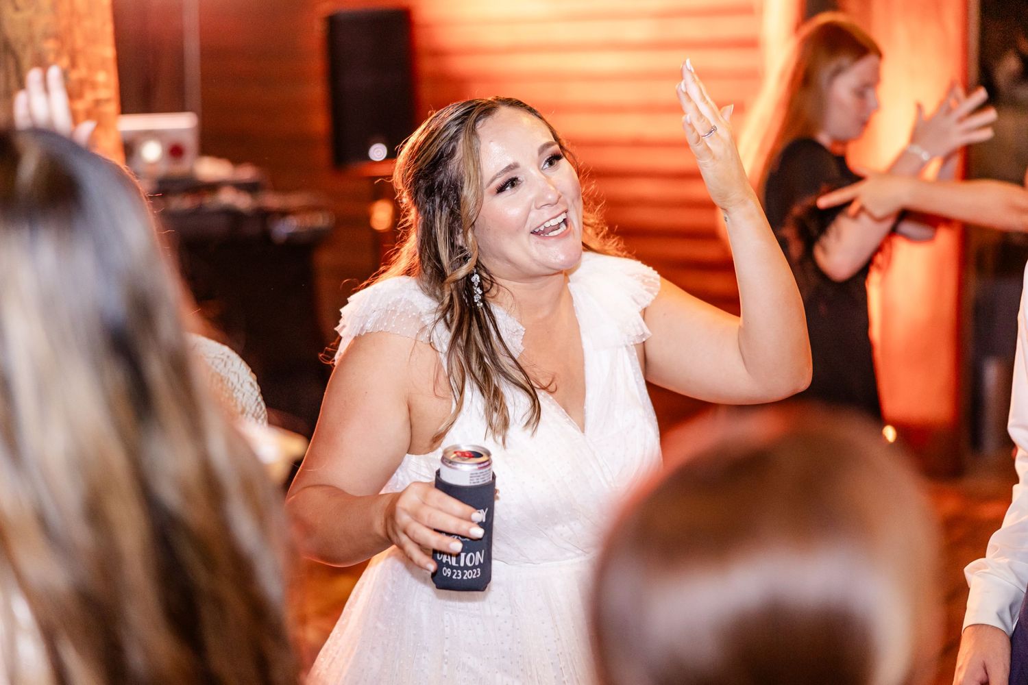 Wedding reception dance floor filled with celebrating guests in warm lighting.