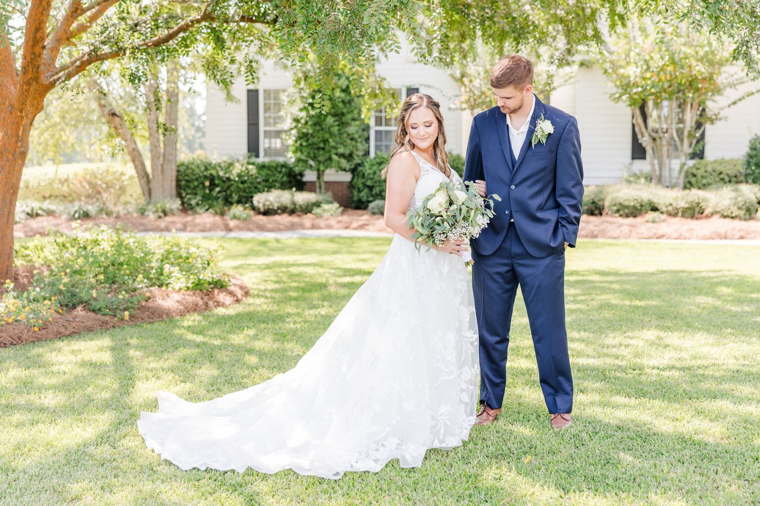Romantic outdoor wedding portraits with bride holding eucalyptus bouquet beside groom in navy suit.