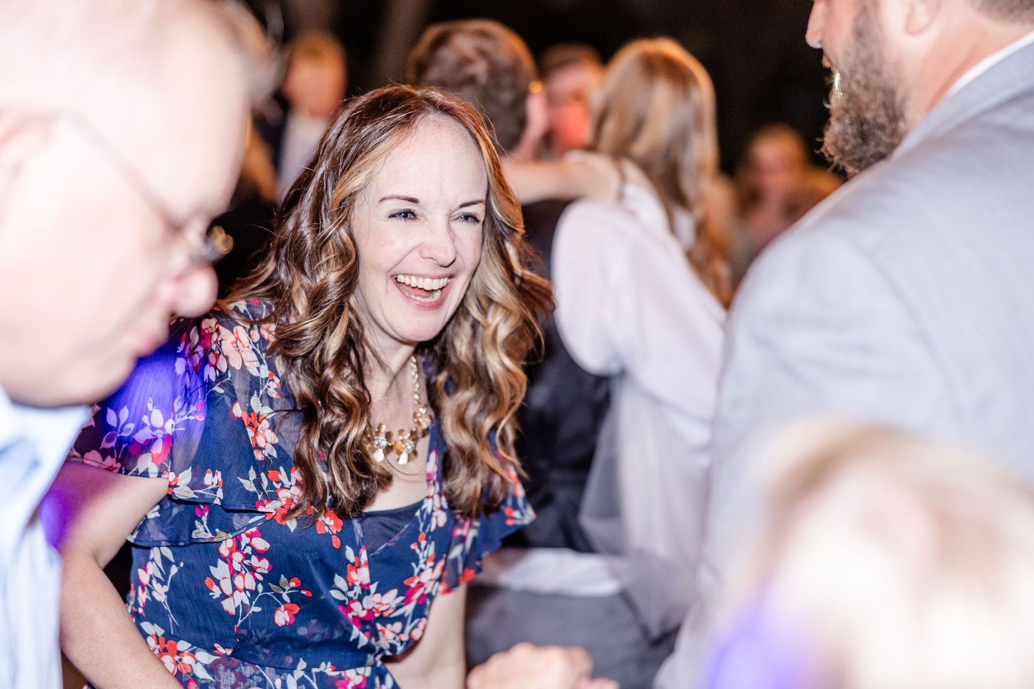Guest laughing during a lively reception celebration with colorful lighting.