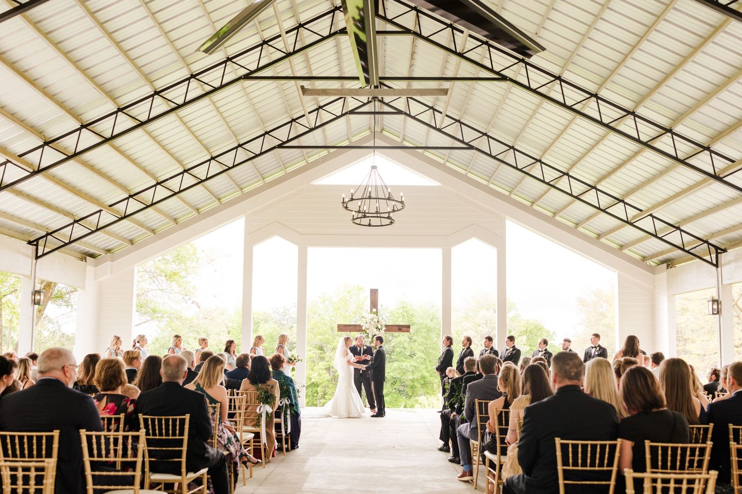 Wedding ceremony taking place in an elegant white pavilion with guests seated in rows.
