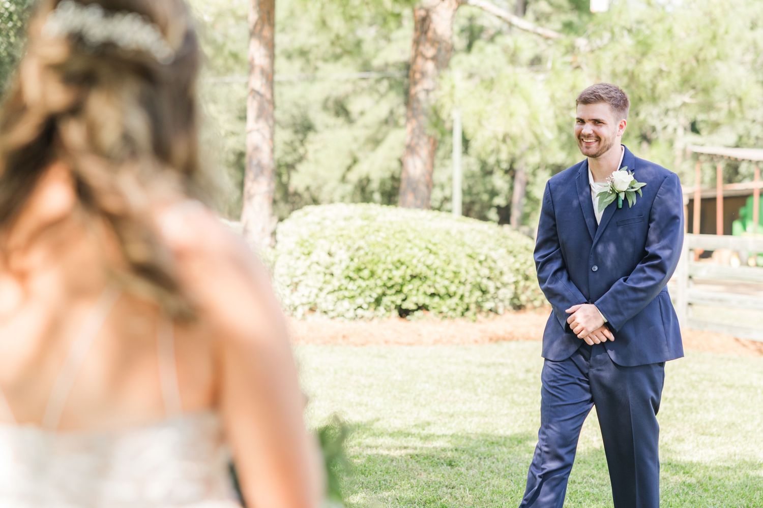 Wedding couple's first look moment photographed in a sun-dappled garden setting.