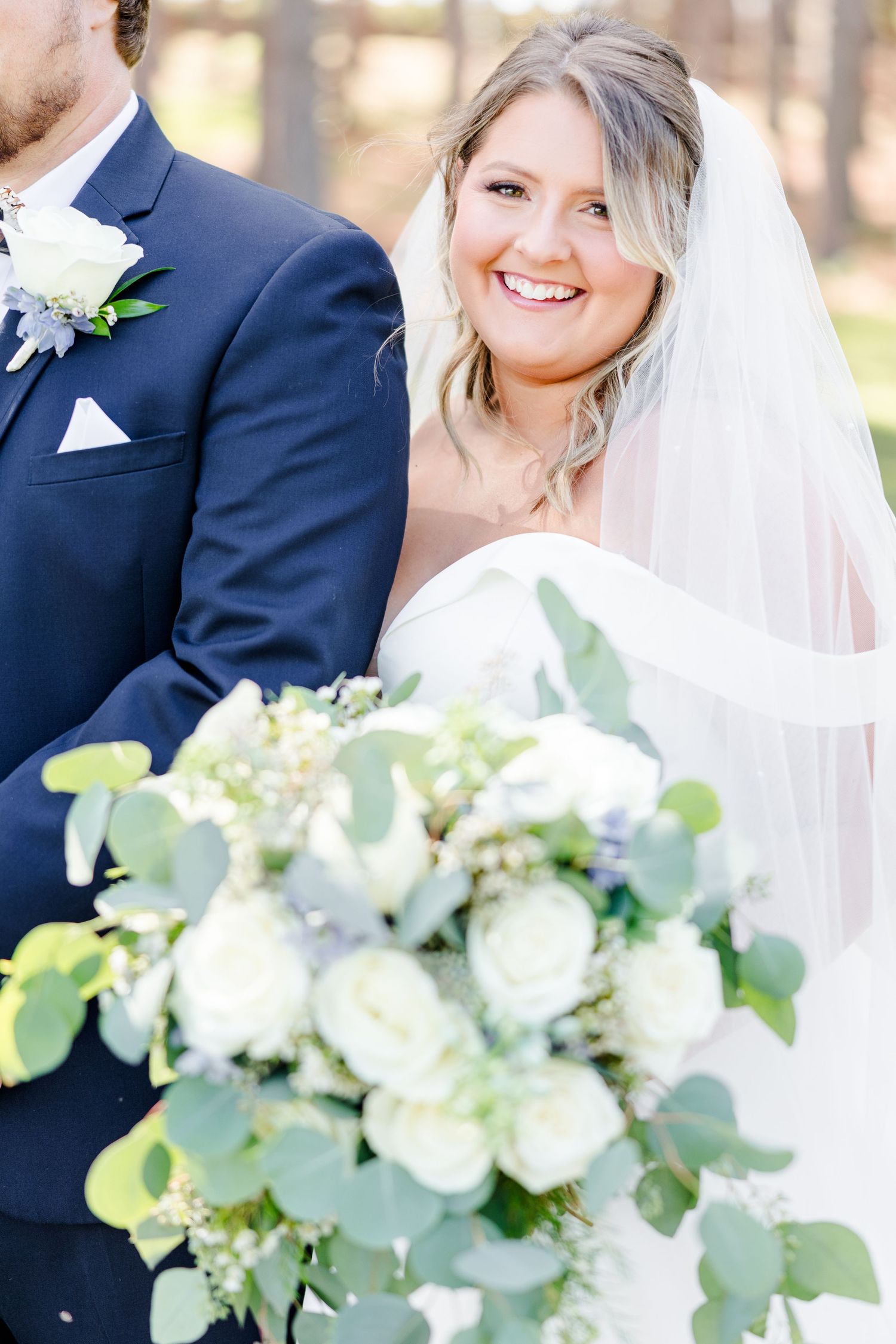 Close-up wedding photo featuring elegant white and green bouquet with eucalyptus leaves.