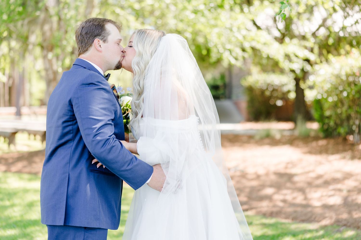Romantic wedding couple sharing a moment in a garden with dappled sunlight.