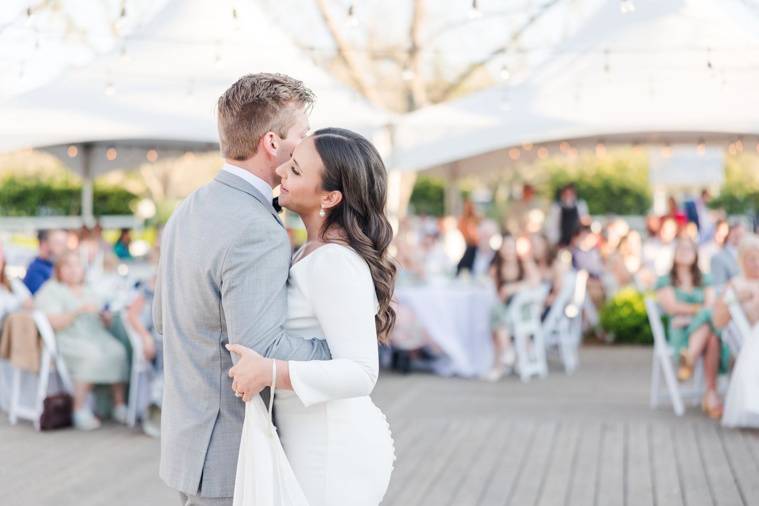 Romantic outdoor wedding reception scene with string lights and white decor.