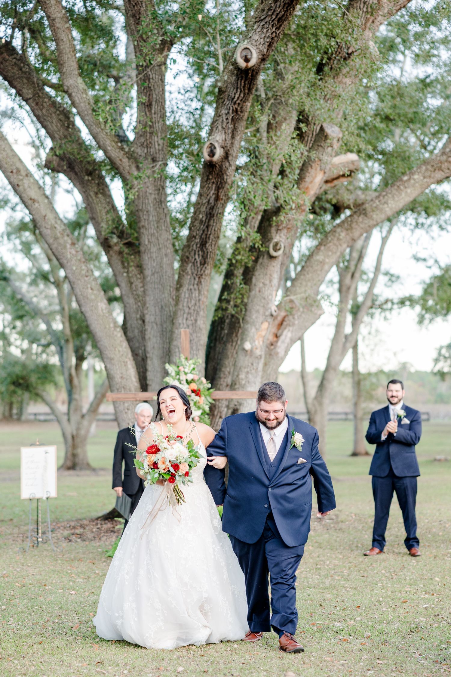Fun wedding party photos taken on grassy grounds beneath large oak trees.