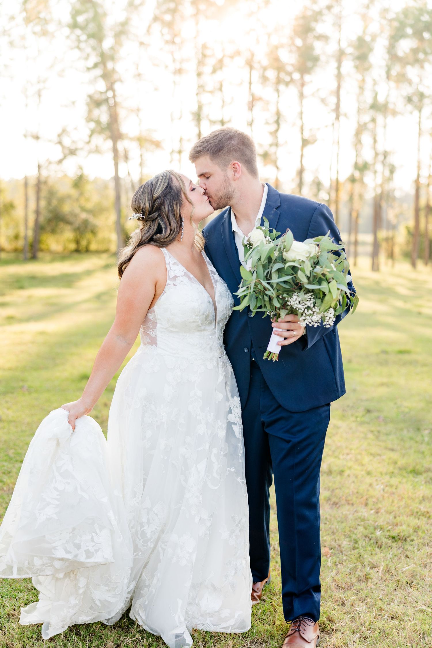 Romantic wedding couple shares intimate moments in a sunlit outdoor setting.