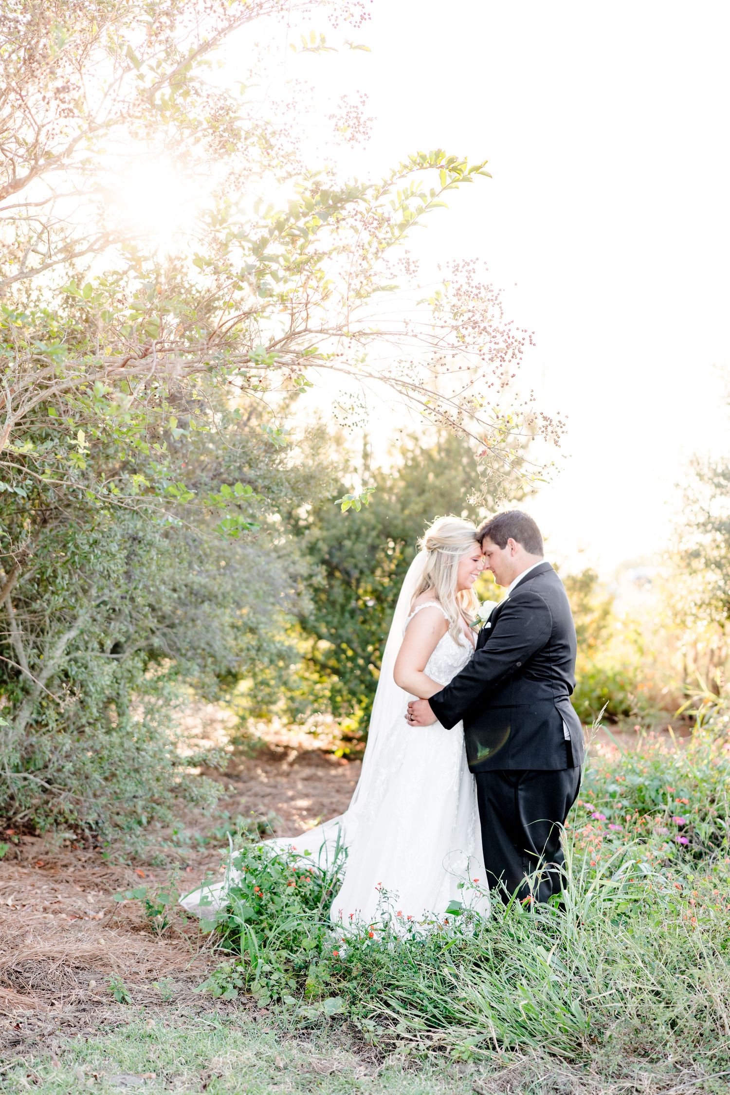 A tender wedding moment captured in a natural outdoor setting during golden hour.