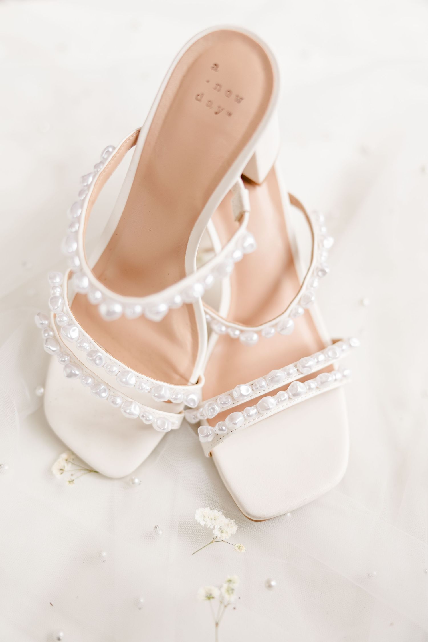 Pearl-embellished white bridal sandals on light background.